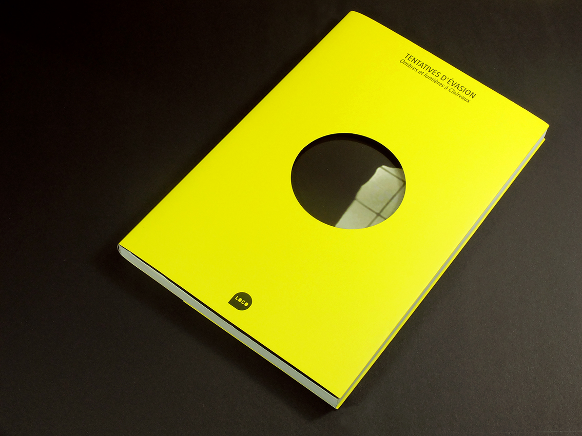 Un livre jaune, intitulé « Tentatives d'évasion », présente une découpe circulaire sur la couverture et des touches de design graphique. Sur fond sombre, sa présentation unique suscite la curiosité.