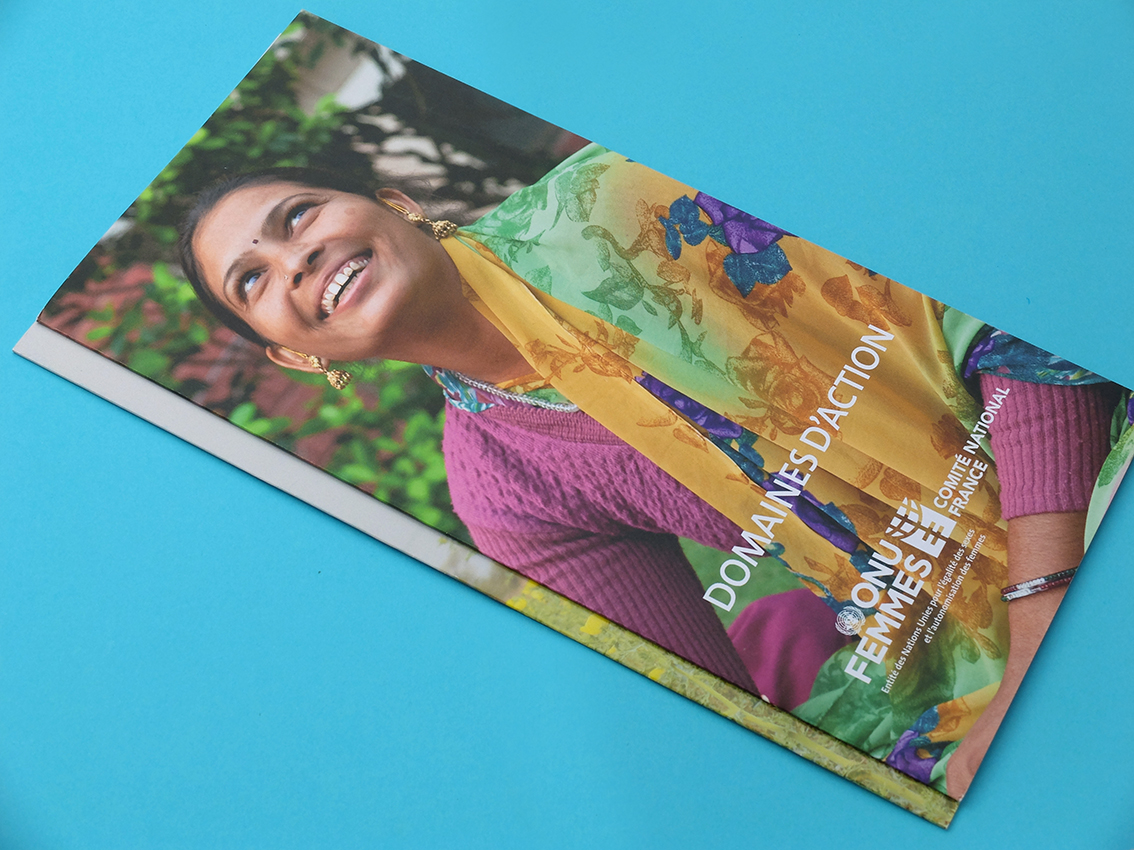 Femme souriante en tenue colorée sur une brochure illustrée intitulée « Domaines d'Action » avec le logo « ONU FEMMES » et le texte « Fiche Technique », sur fond bleu, présentant un design graphique dynamique.