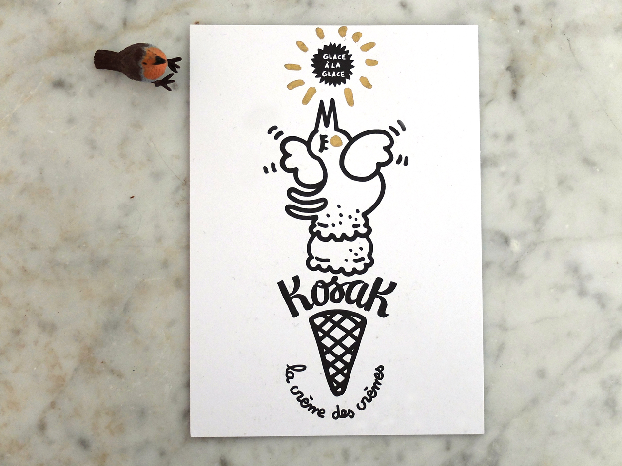 Illustration d'une créature ressemblant à un coq perchée au sommet d'un cornet de crème glacée, accompagnée du texte français « Glace à la glace », « Koosk » et « la crème des crèmes ». Une petite figure d'oiseau repose sur la surface en marbre, rappelant le style de dessin ludique de Laurence Chéné.