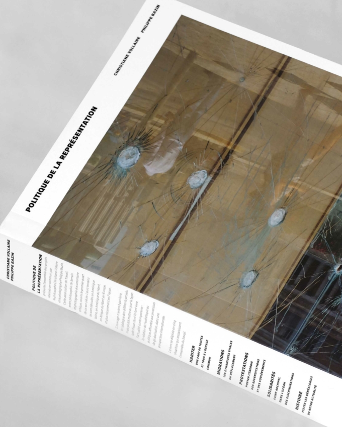 Un magazine dont la couverture en verre est criblée d'impacts de balles, intitulé « Politique de la Représentation », repose sur une surface grise. Du texte apparaît sur les bords latéraux et inférieur.