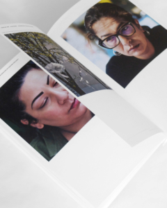 Livre ouvert présentant des photos en gros plan de deux femmes : l'une porte des lunettes et des boucles d'oreilles en anneau, l'autre a les cheveux foncés et les sourcils bien dessinés.