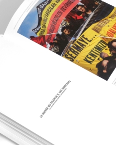 Un livre ouvert montre une photo de personnes brandissant des banderoles de manifestation jaunes et rouges au-dessus d'une page sur laquelle figure le texte en français « LE MUSÉE DU SILENCE ET LES INNOCENTS ».