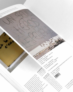 Un livre ouvert montrant une photographie d'un graffiti sur lequel on peut lire « UN SEUL HÉROS LE PEUPLE » sur un mur, avec une autre photo plus petite et un texte sur la page en face.